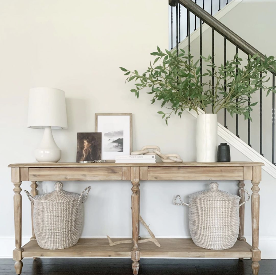 entryway table with woven baskets and a vase of greens