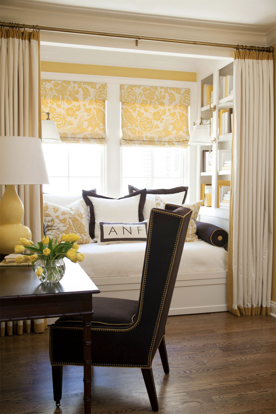 window seat in bay window with yellow roman shades