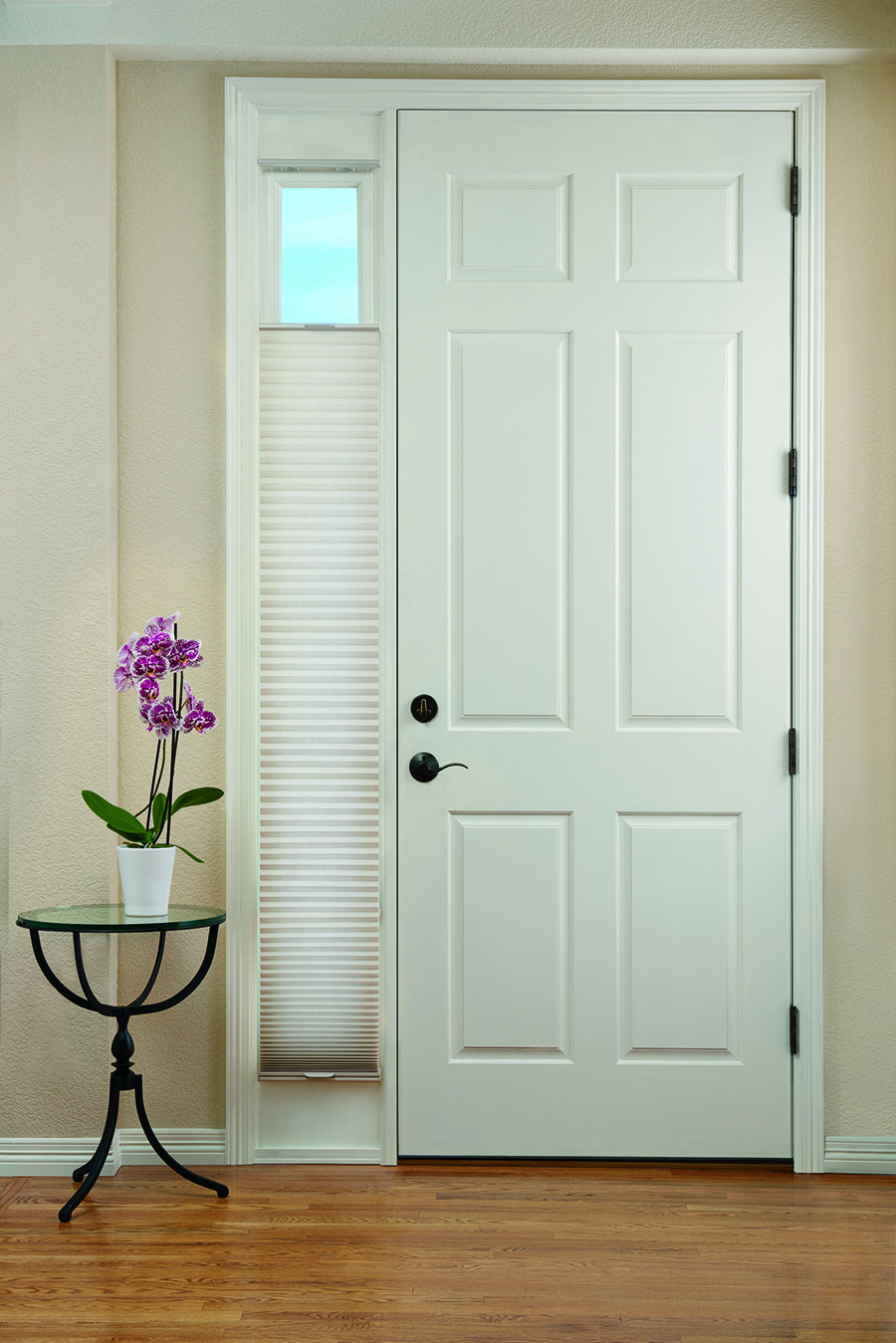 Honeycomb shades on sidelight of entryway door.