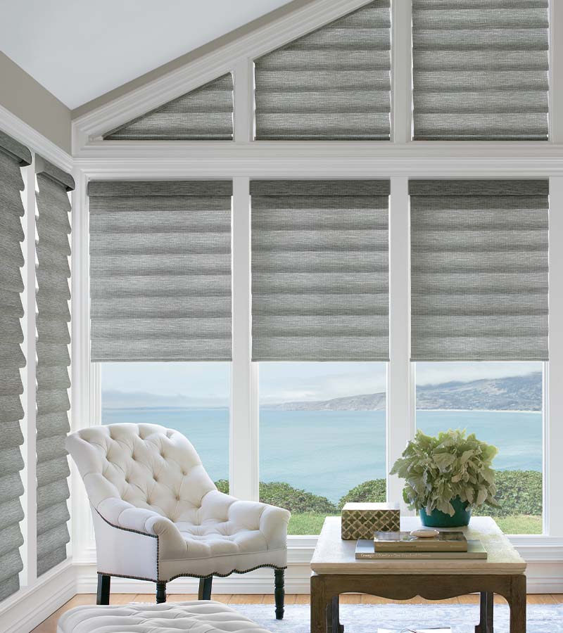 angled windows covered with gray roman shades