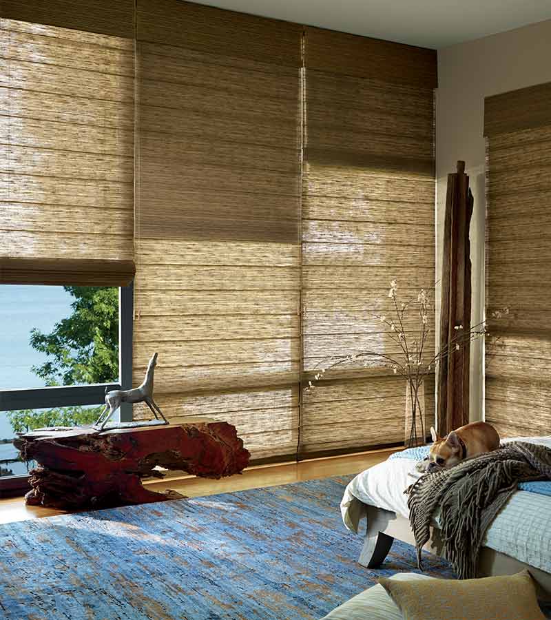 master bedroom with large floor to ceiling window treatments in caramel shades in organic materials