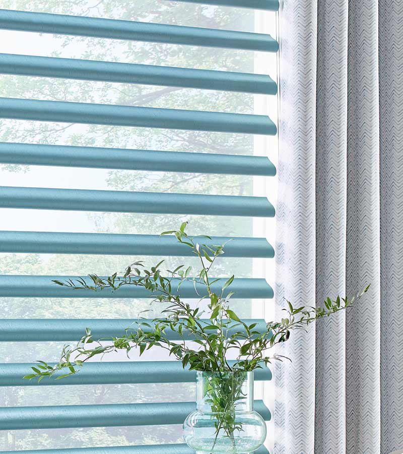 detail of blue piroutte window shades and designer drapes next to house plants roseville, ca