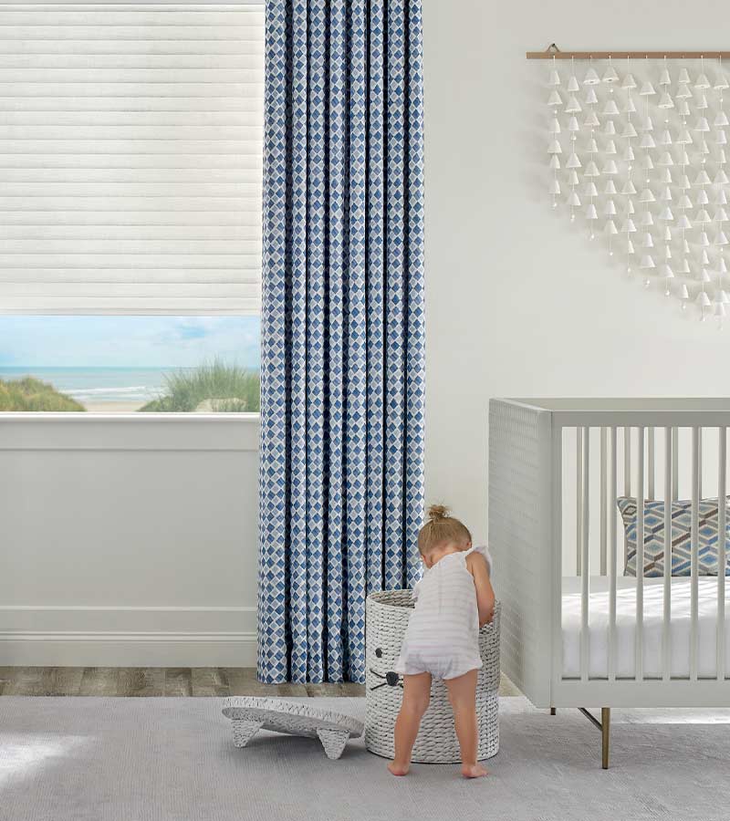 little girl playing in nursery with blue patterned drapery overlooking lake in Rocklin, CA