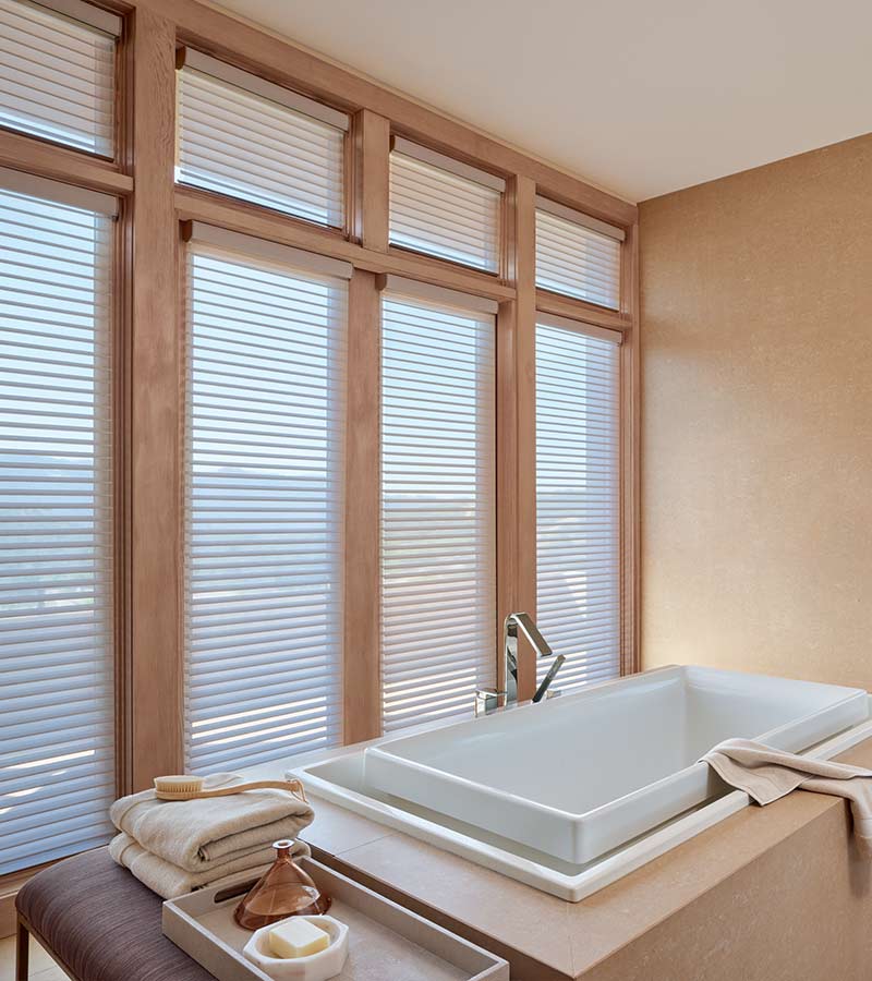 master bathroom sunken tub next to privacy shades framed with warm wood