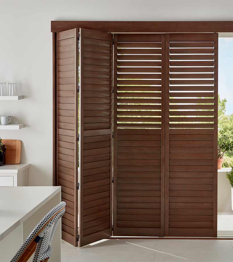 bifold wood grain shutters in dark mahogany in white kitchen