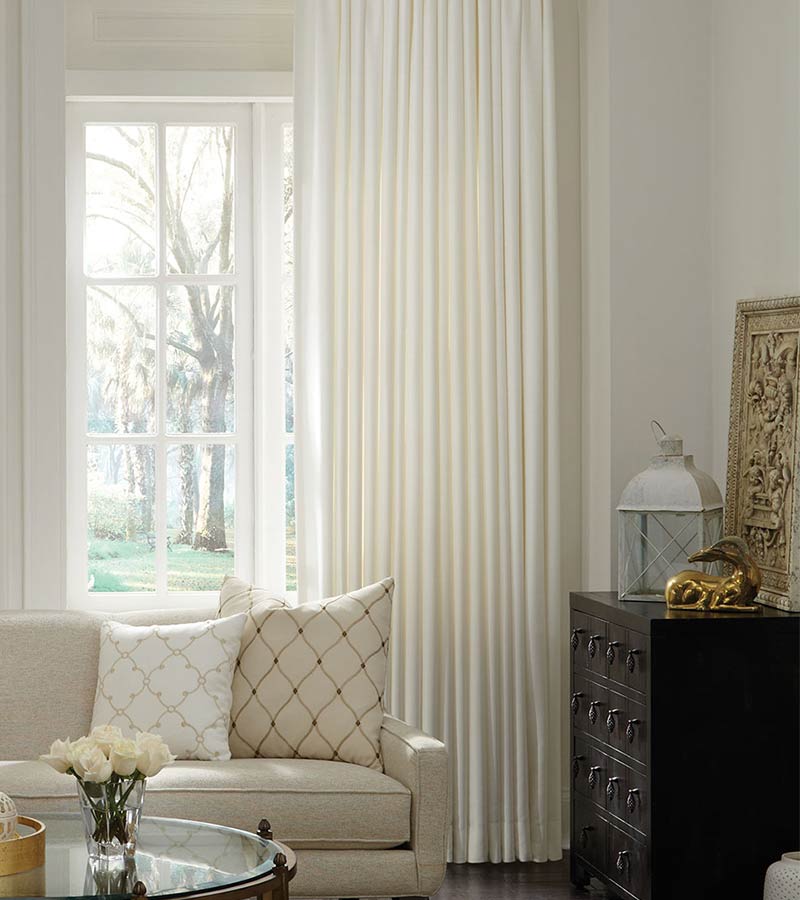 cream floor to ceiling drapery panels in traditional living room with white couch and cushions