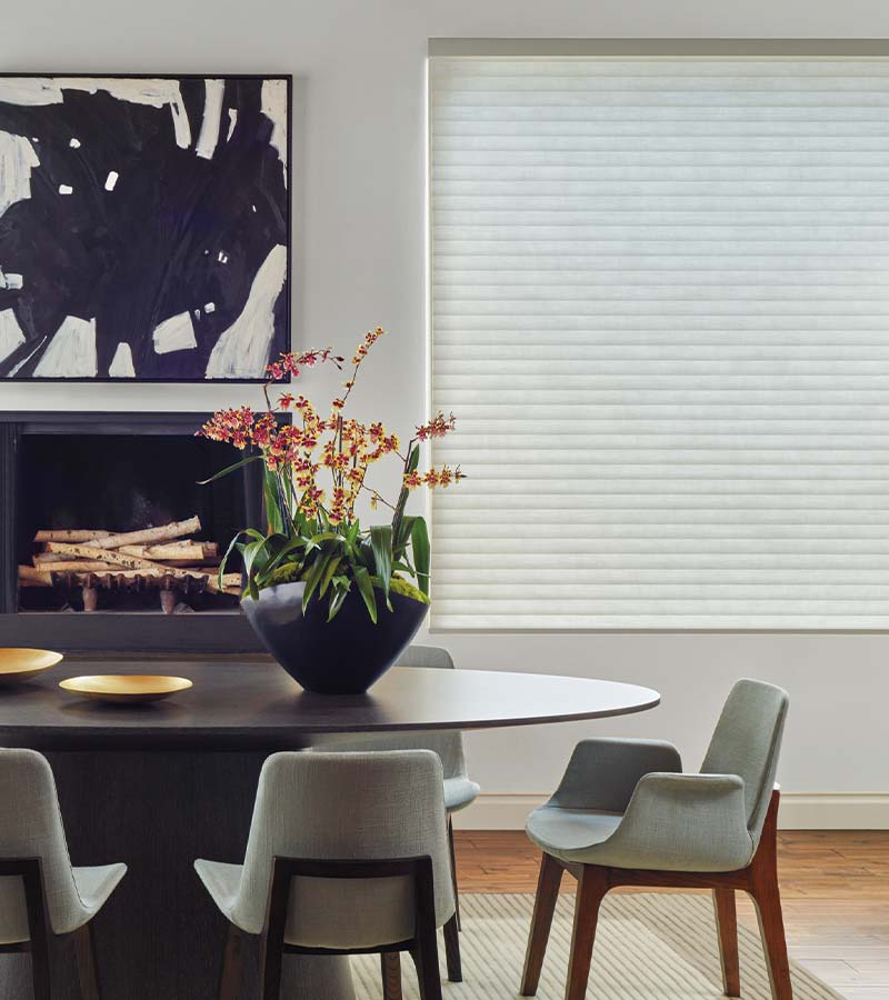 Dining area featuring a closed white honeycomb shade and round table