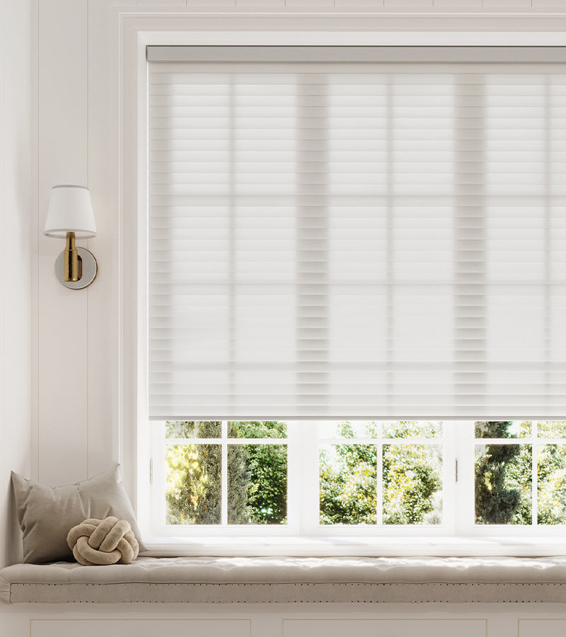 Light-filtering white cellular window shade above a built-in window seat in a bright living room